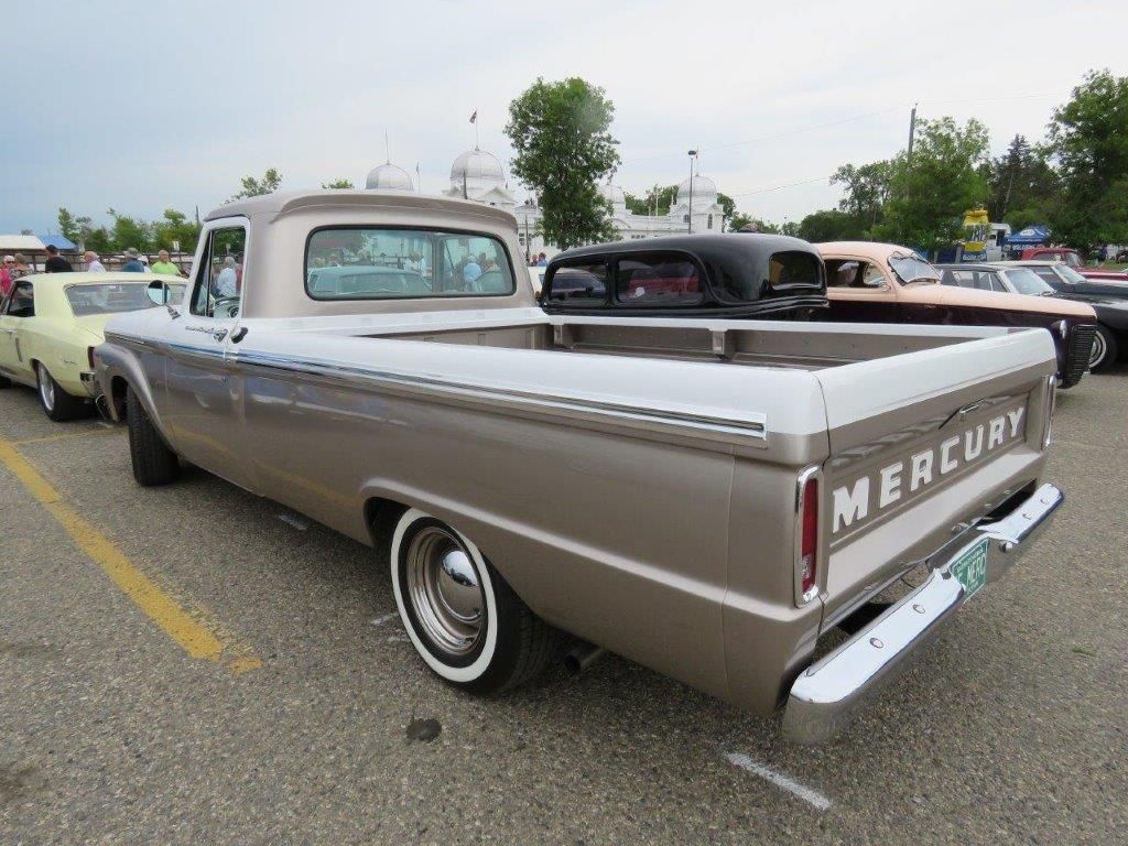A mercury truck is parked in a parking lot with other cars.