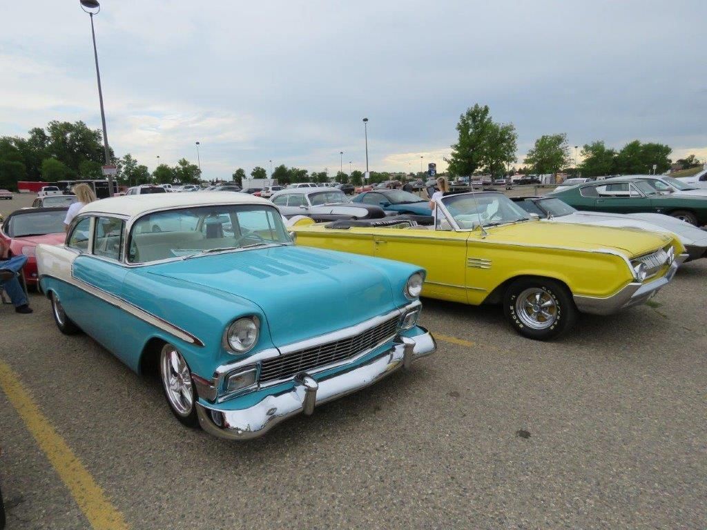 Two old cars are parked next to each other in a parking lot.