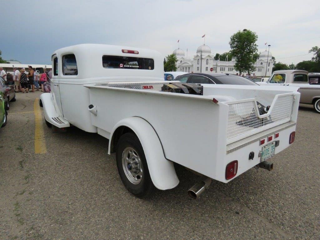 A white truck with a trailer attached to it is parked in a parking lot.