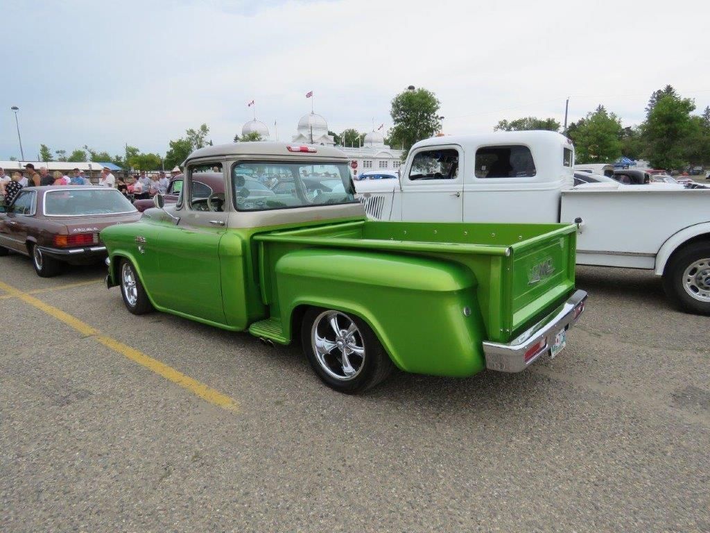 A green truck is parked next to a white truck
