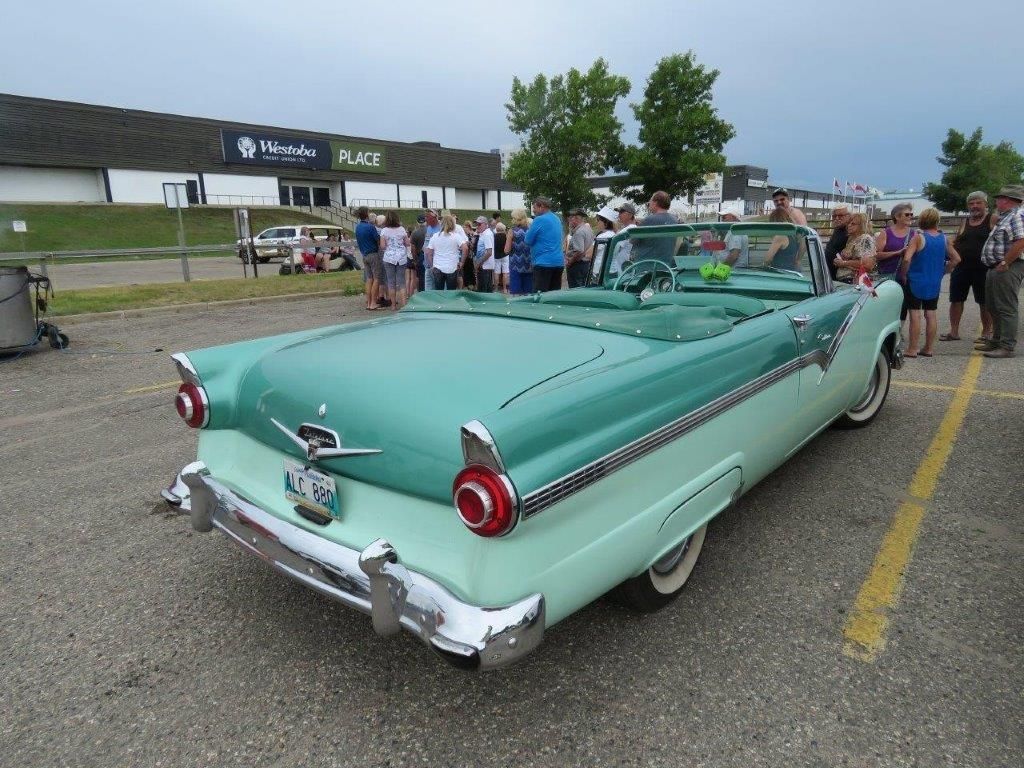 A green car is parked in a parking lot in front of a building that says place