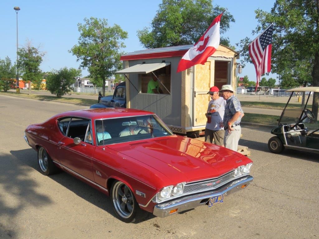 A red car is parked in front of a trailer with a canadian flag on it