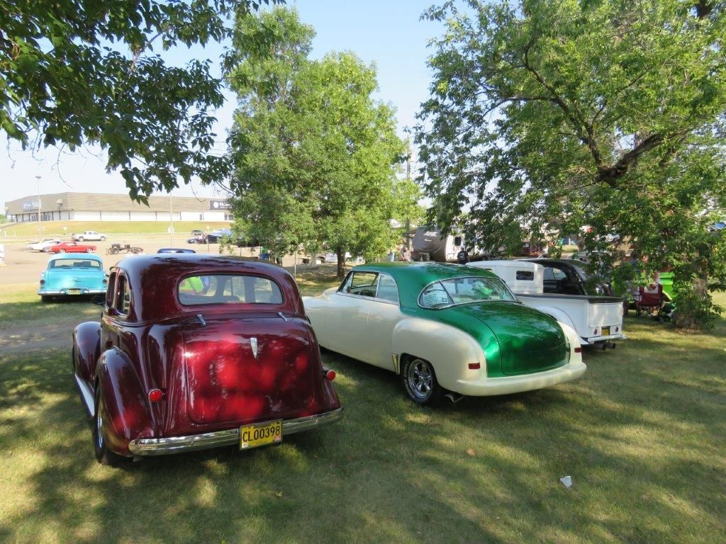 Three old cars are parked in a grassy field.