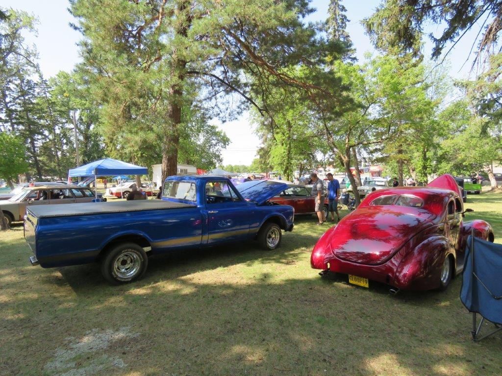 A blue truck is parked next to a red car at a car show.