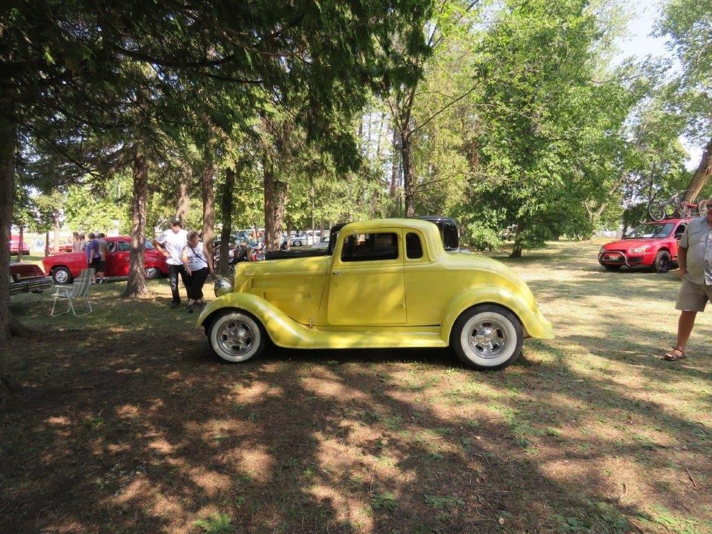 A yellow car is parked in a grassy field.