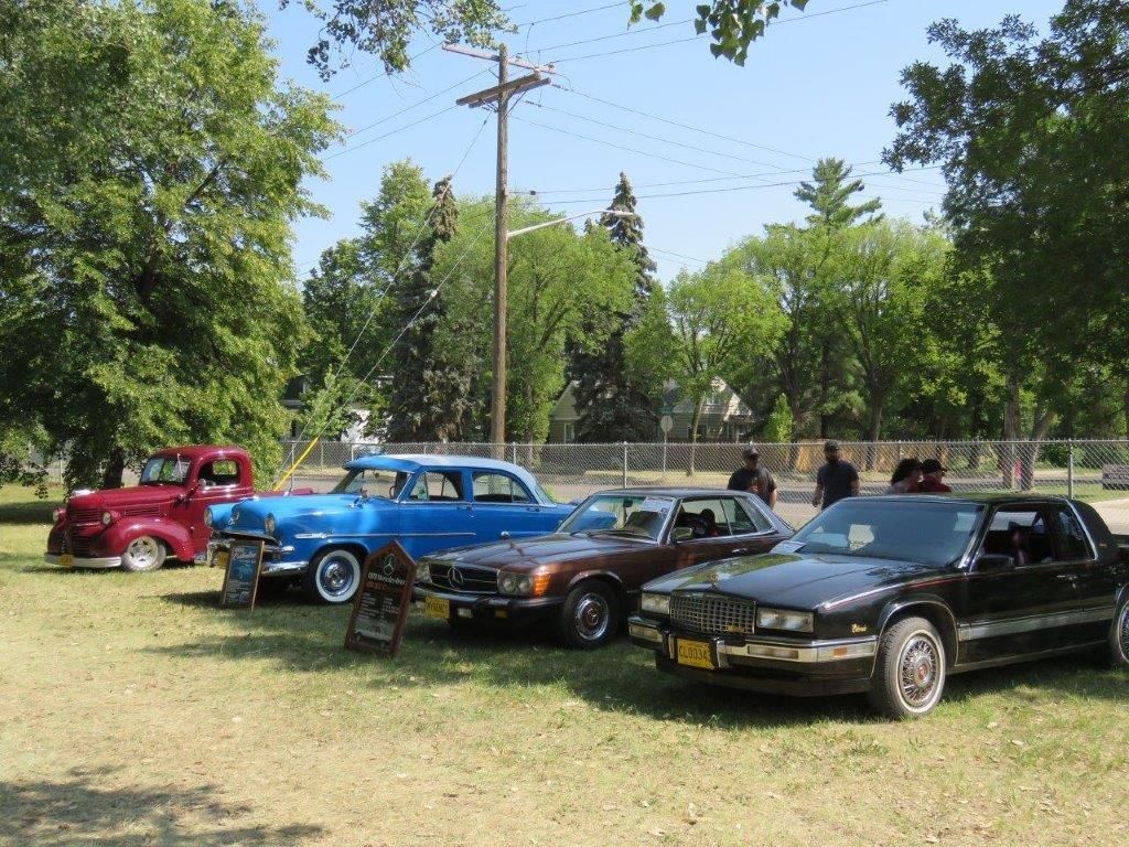 A group of cars are parked in a grassy field.