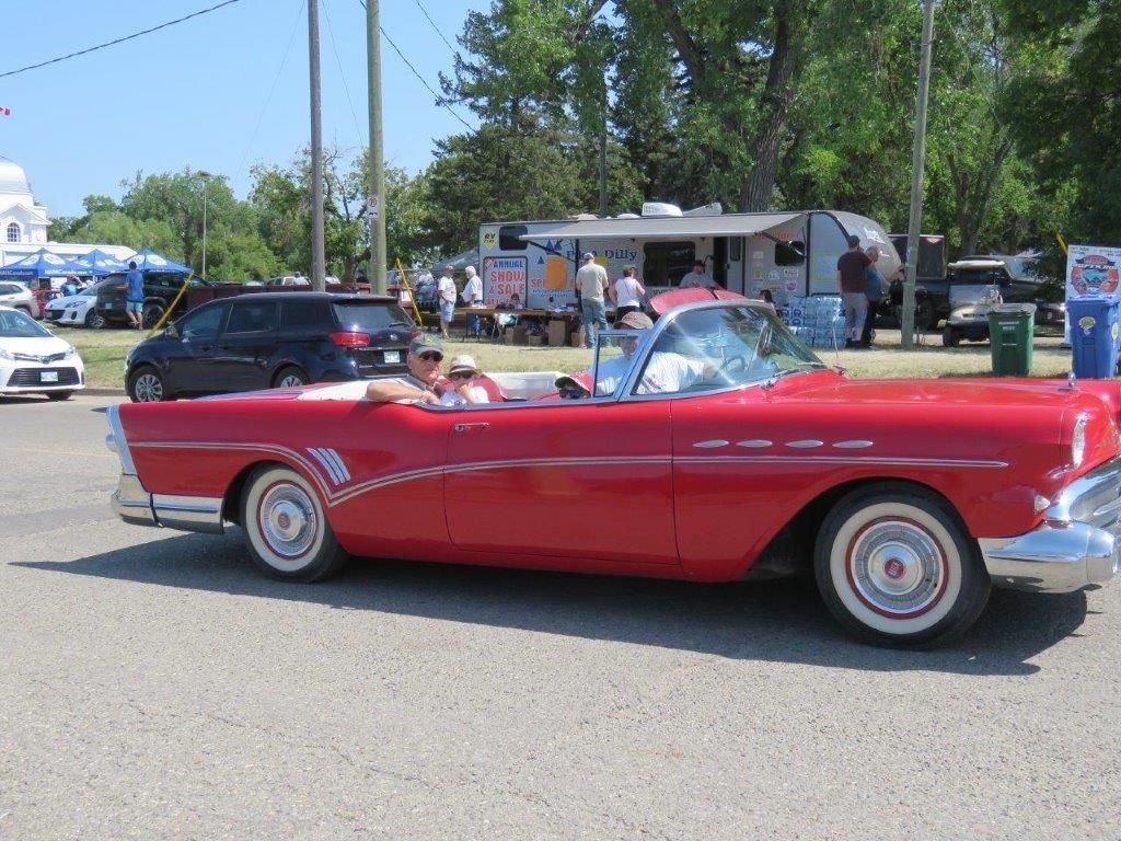 A red car with white tires is parked in a parking lot.