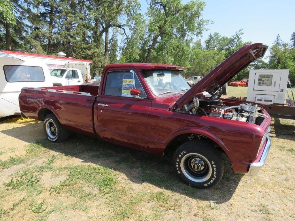 A red truck with the hood up is parked in a field.