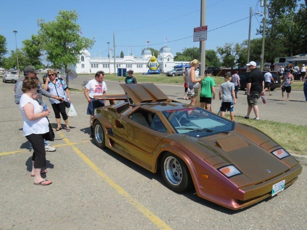 A group of people are standing around a car in a parking lot