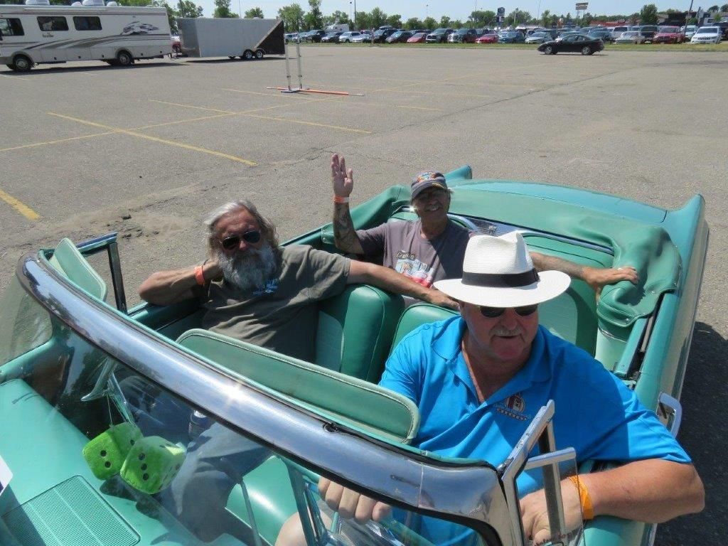 Two men are sitting in a green car in a parking lot