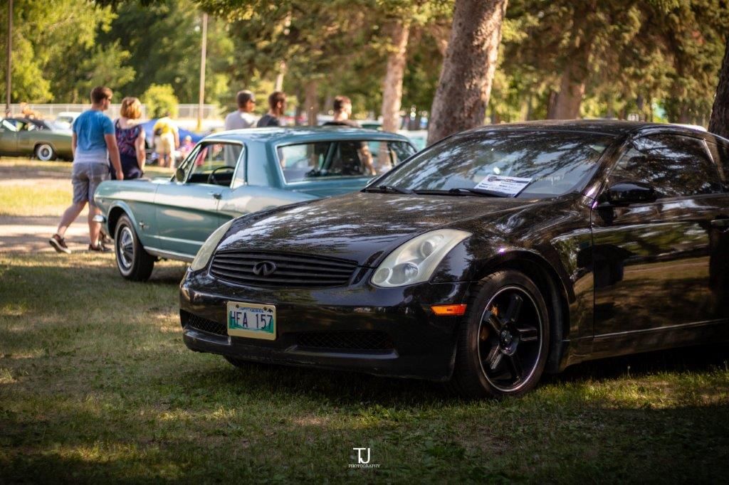 Two cars are parked next to each other in the grass at a car show.