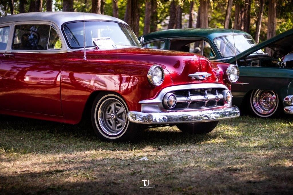 A red car is parked next to a green car at a car show.