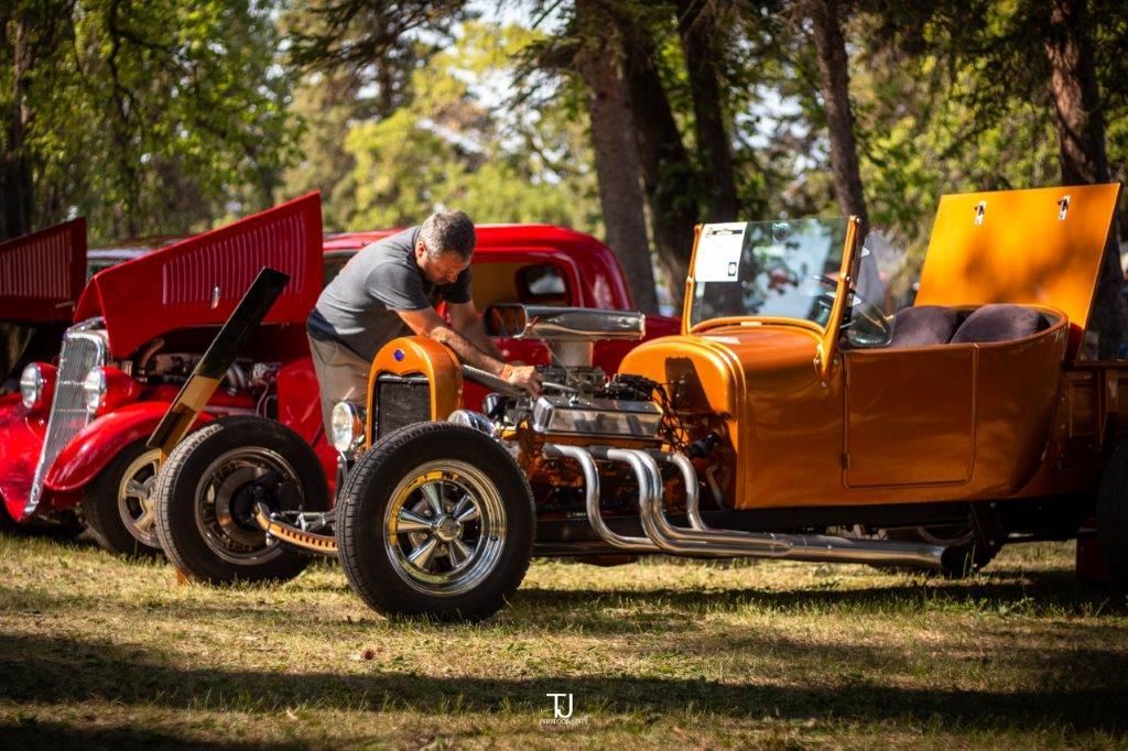 A man is working on a car at a car show.