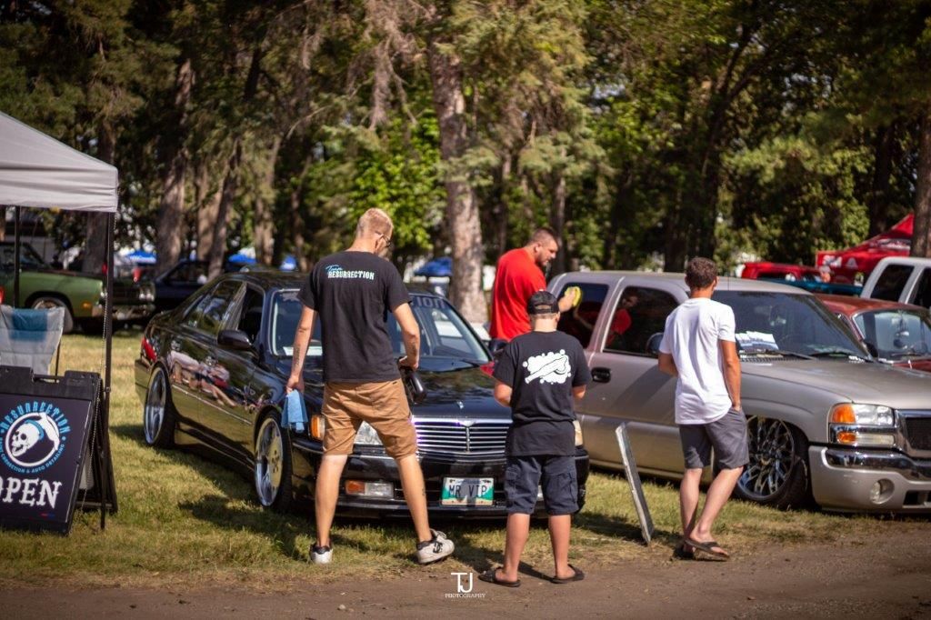 A group of people are standing around a car at a car show.