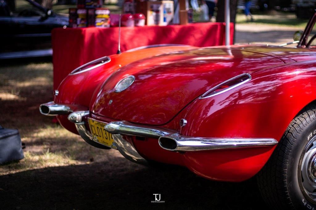 Two red cars are parked next to each other at a car show.