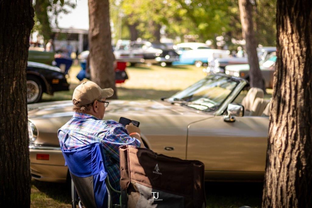 A man in a wheelchair is sitting in front of a car at a car show.