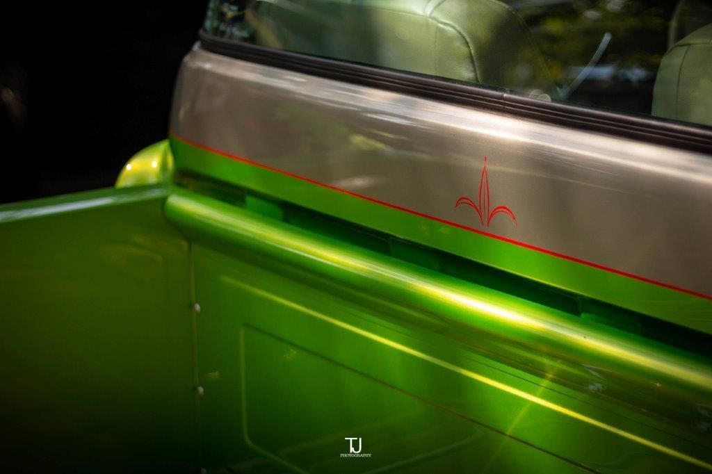 A close up of a green car with a red stripe on the side.