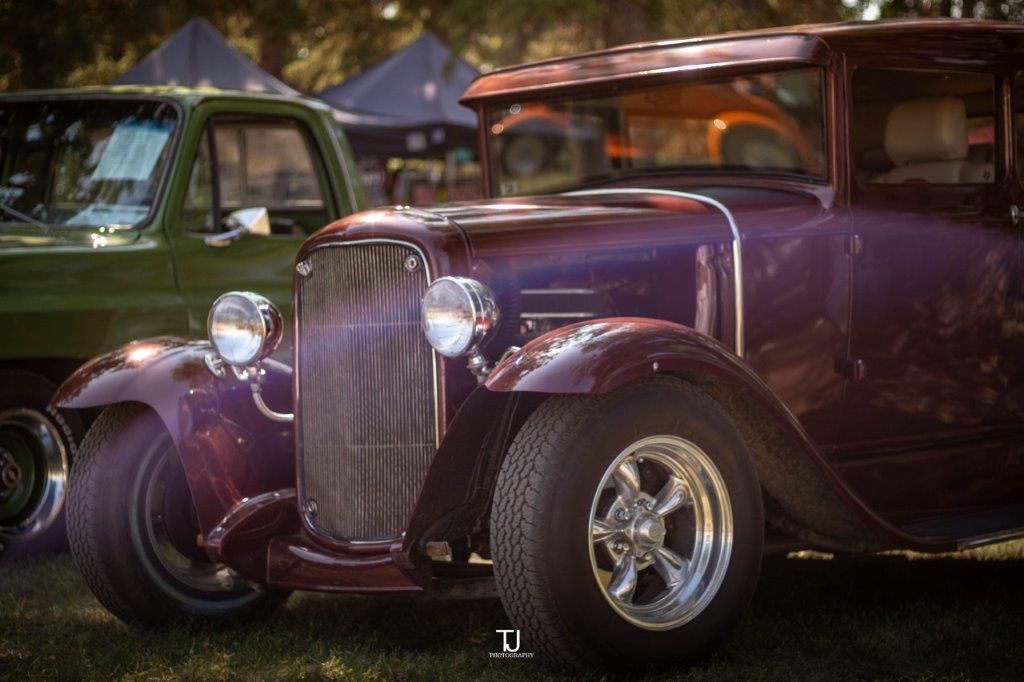 A purple car is parked next to a green truck at a car show.
