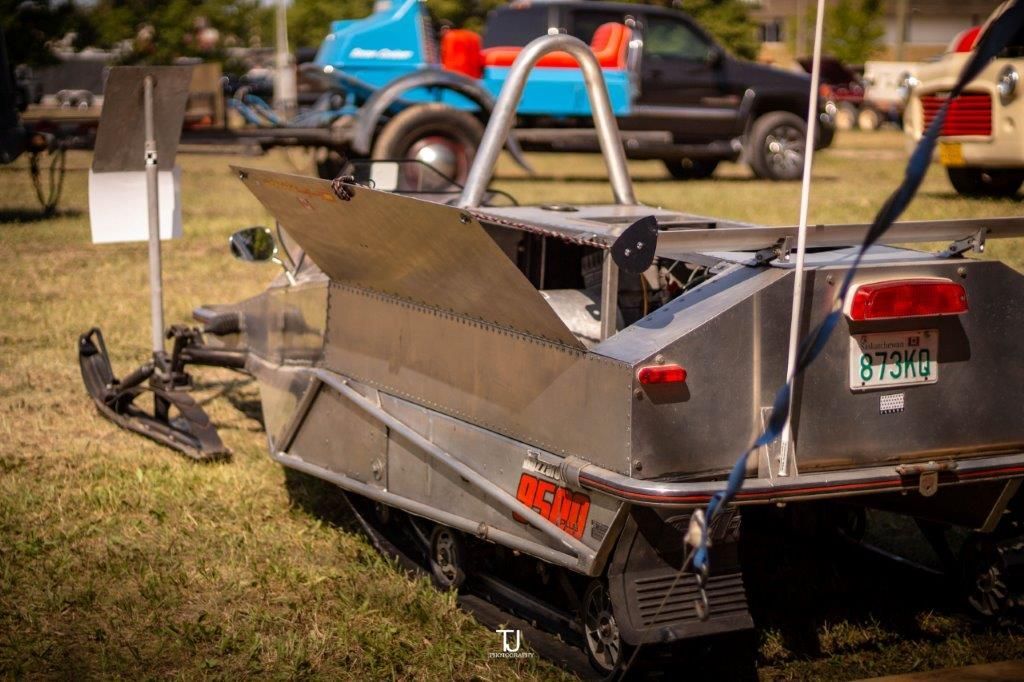 A snowmobile is parked in the grass next to a truck.