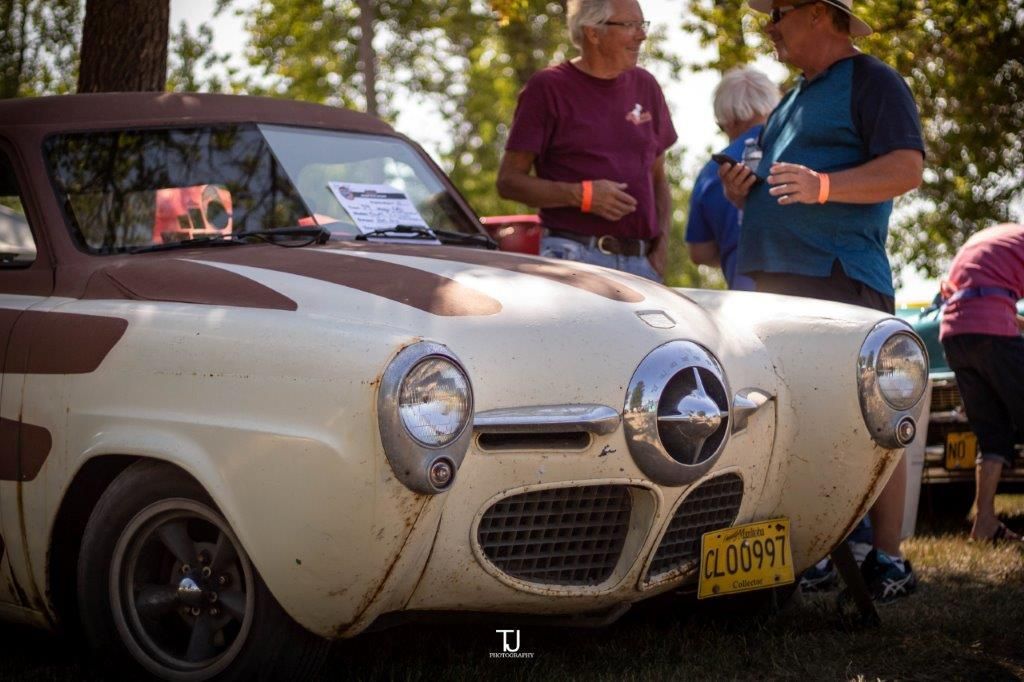 A group of people are standing around a car at a car show.