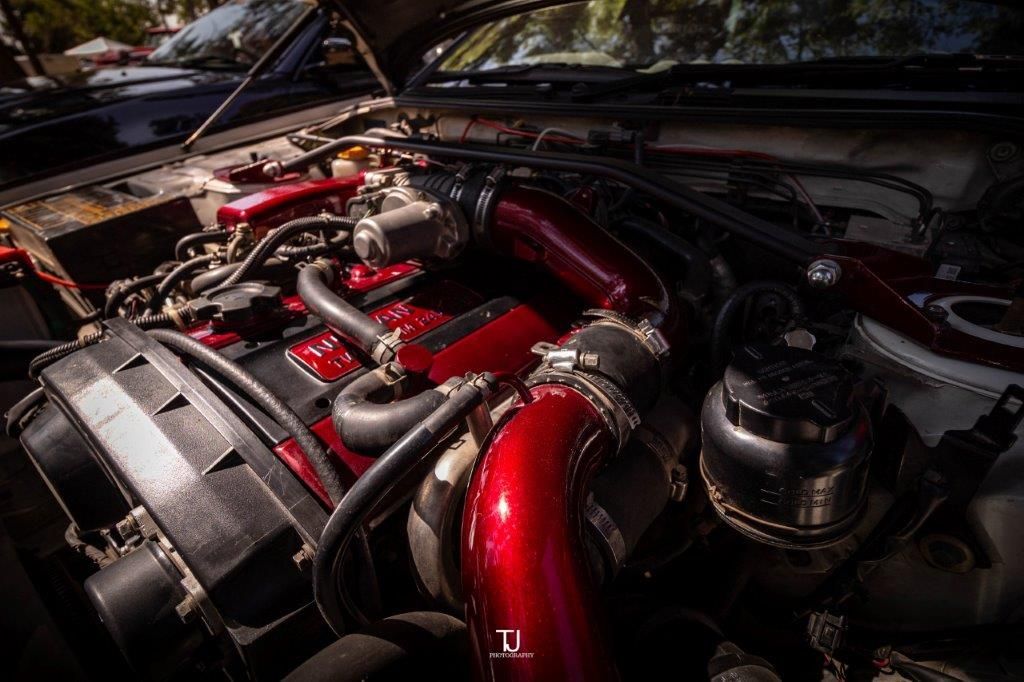 A close up of the engine of a car with the hood open.