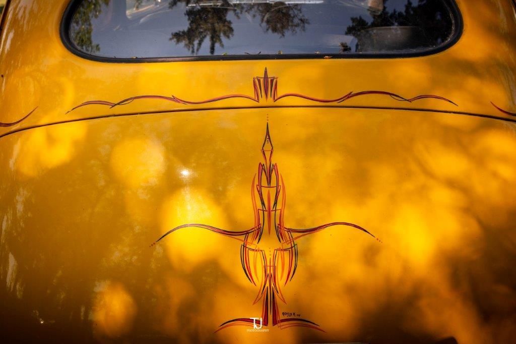 The back of a yellow car with a red design on it.