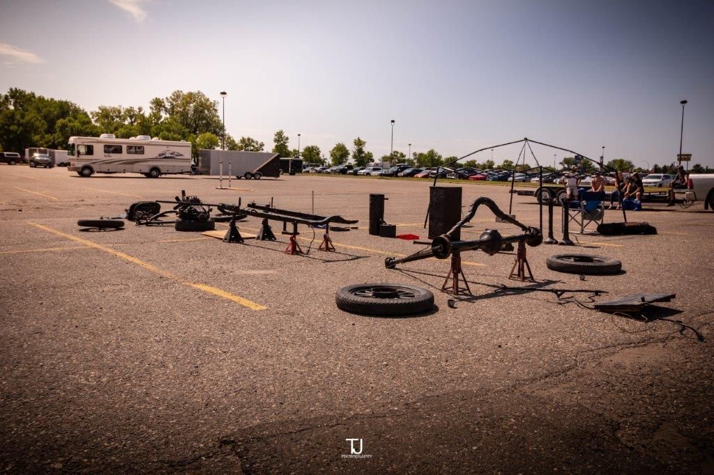 A lot of tires are laying on the ground in a parking lot.