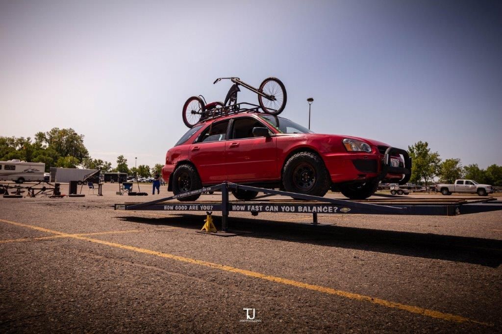 A red car with a bike on the roof is on a trailer.