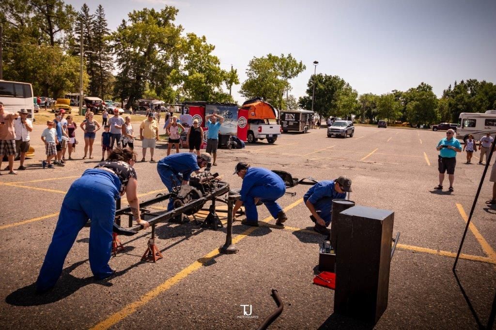 A group of people are working on a vehicle in a parking lot.