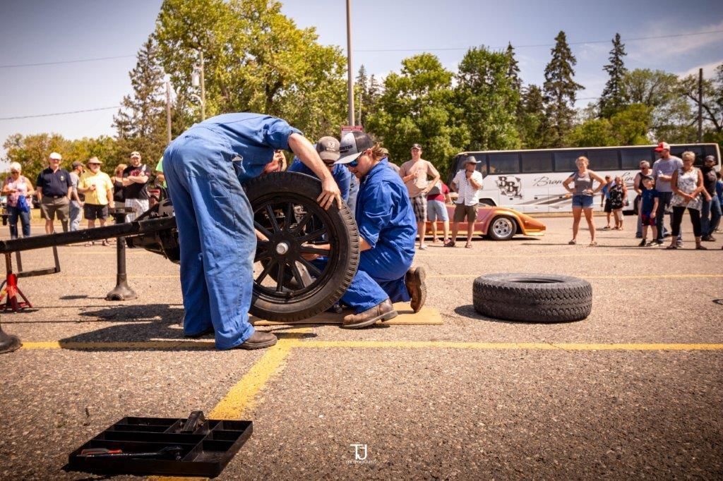 Two men are working on a car in a parking lot.
