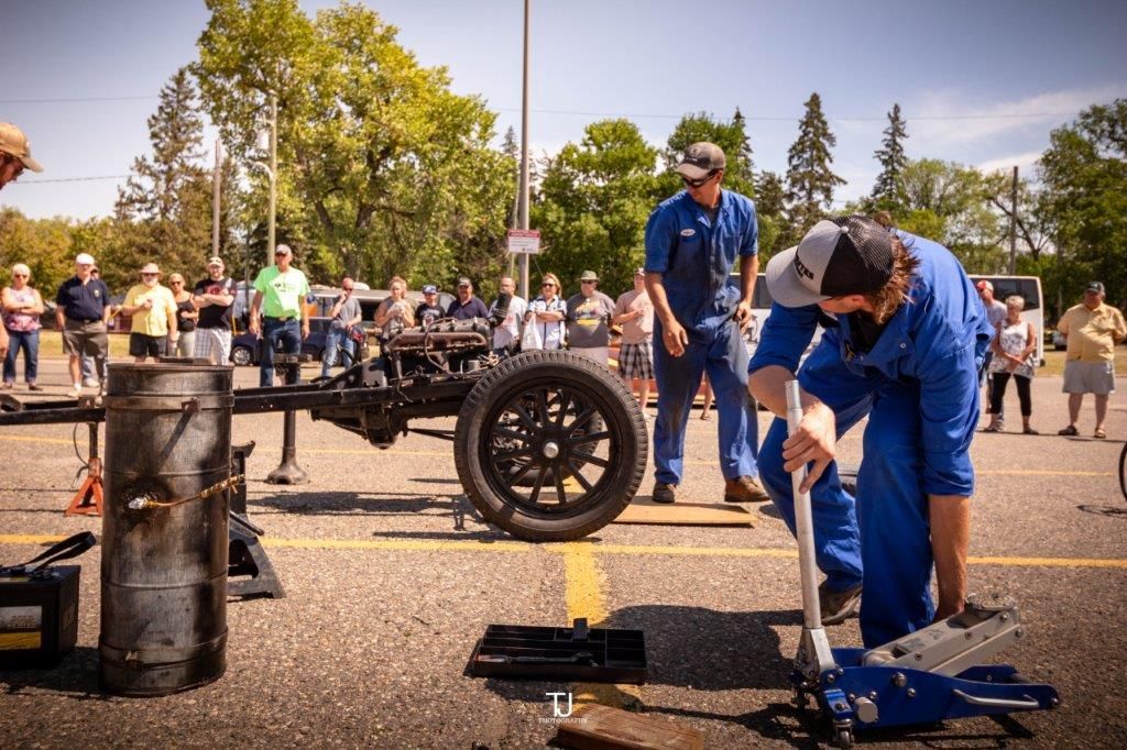 A group of men are working on a car in a parking lot.