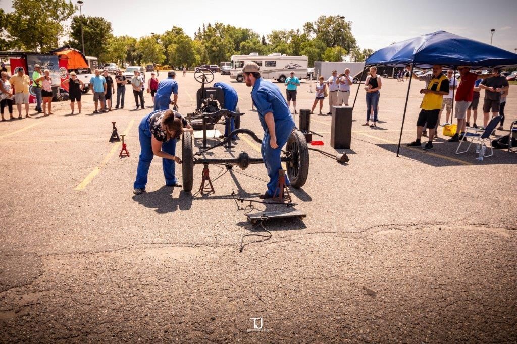 A group of men are working on a car in a parking lot