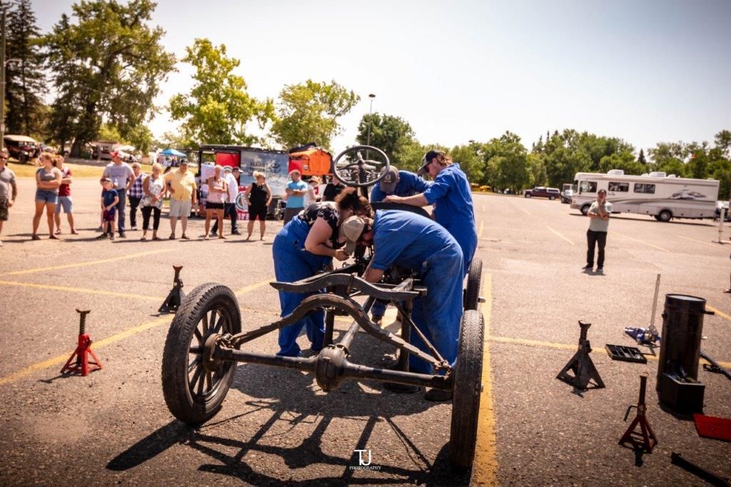 A group of people are working on a car in a parking lot