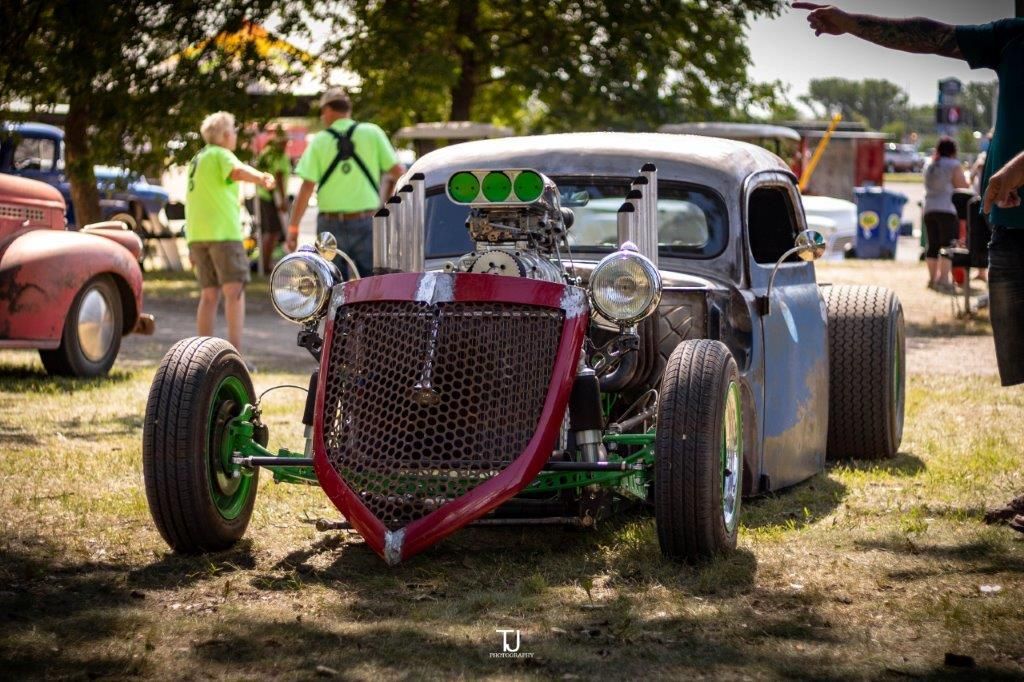 A hot rod is parked in the grass at a car show.