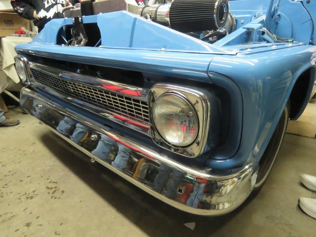 A blue truck with the hood open is sitting in a garage