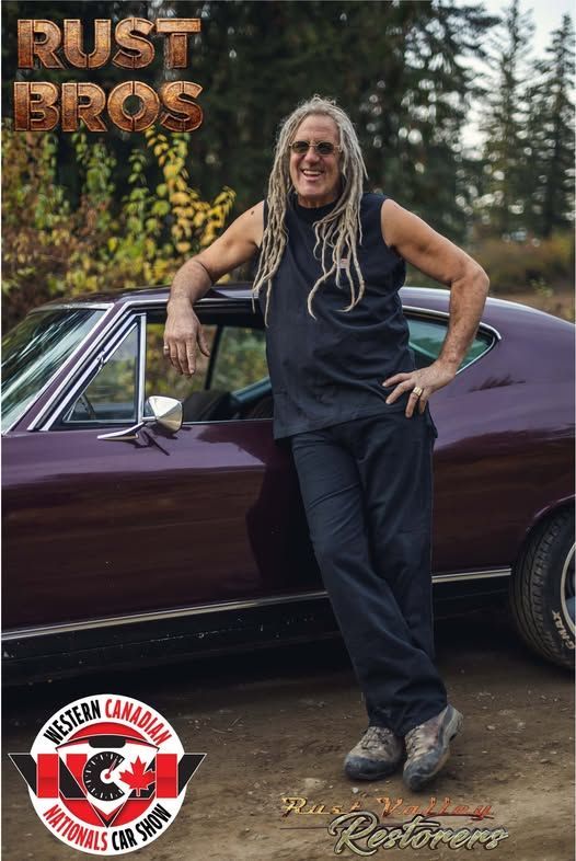 A man with dreadlocks is leaning against a purple car.