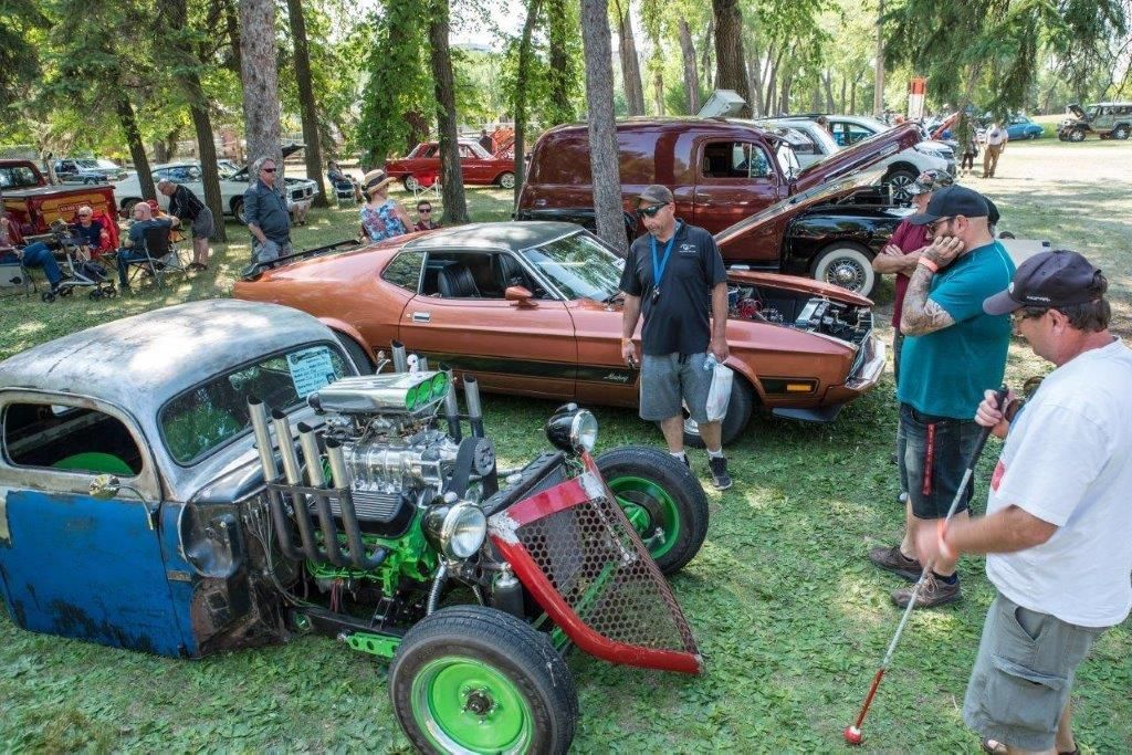 A group of men are looking at cars at a car show.