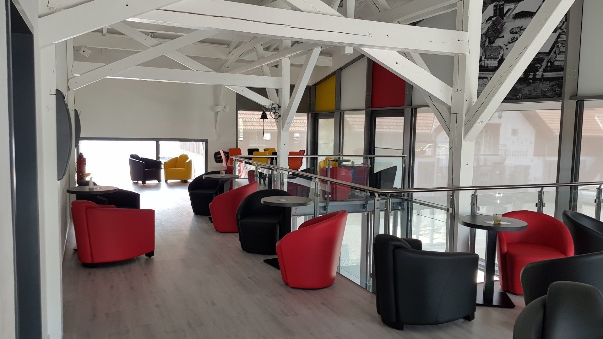 Eine moderne Lounge mit schwarzen und roten Sesseln, die um kleine Tische unter