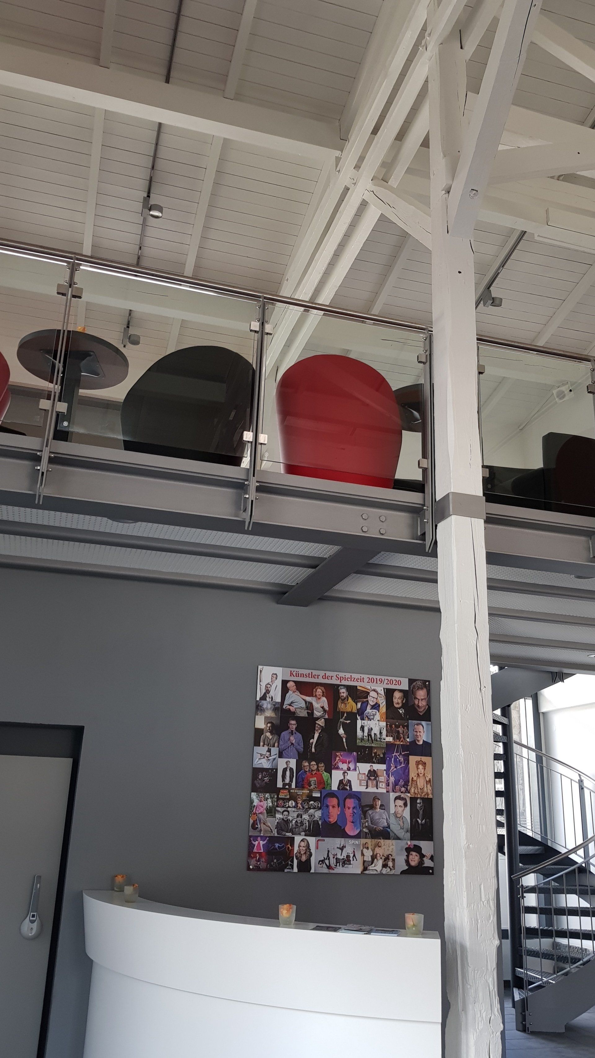 Ein erhöhter Sitzbereich mit Stühlen bietet Blick auf einen Raum, in dem an einer Wand