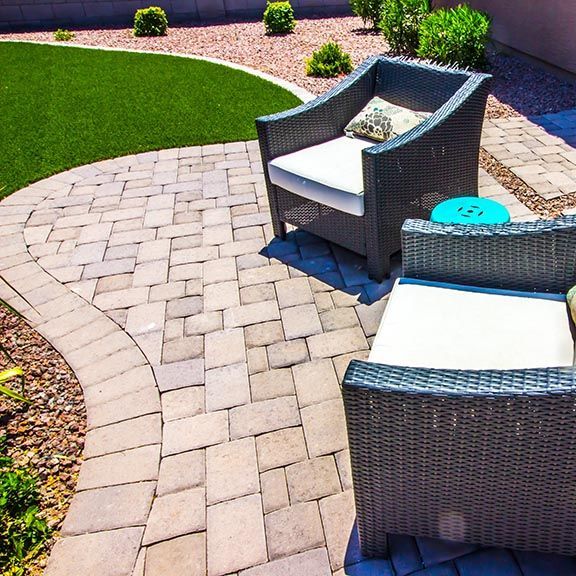 a backyard with a patio , umbrella , and flowers .