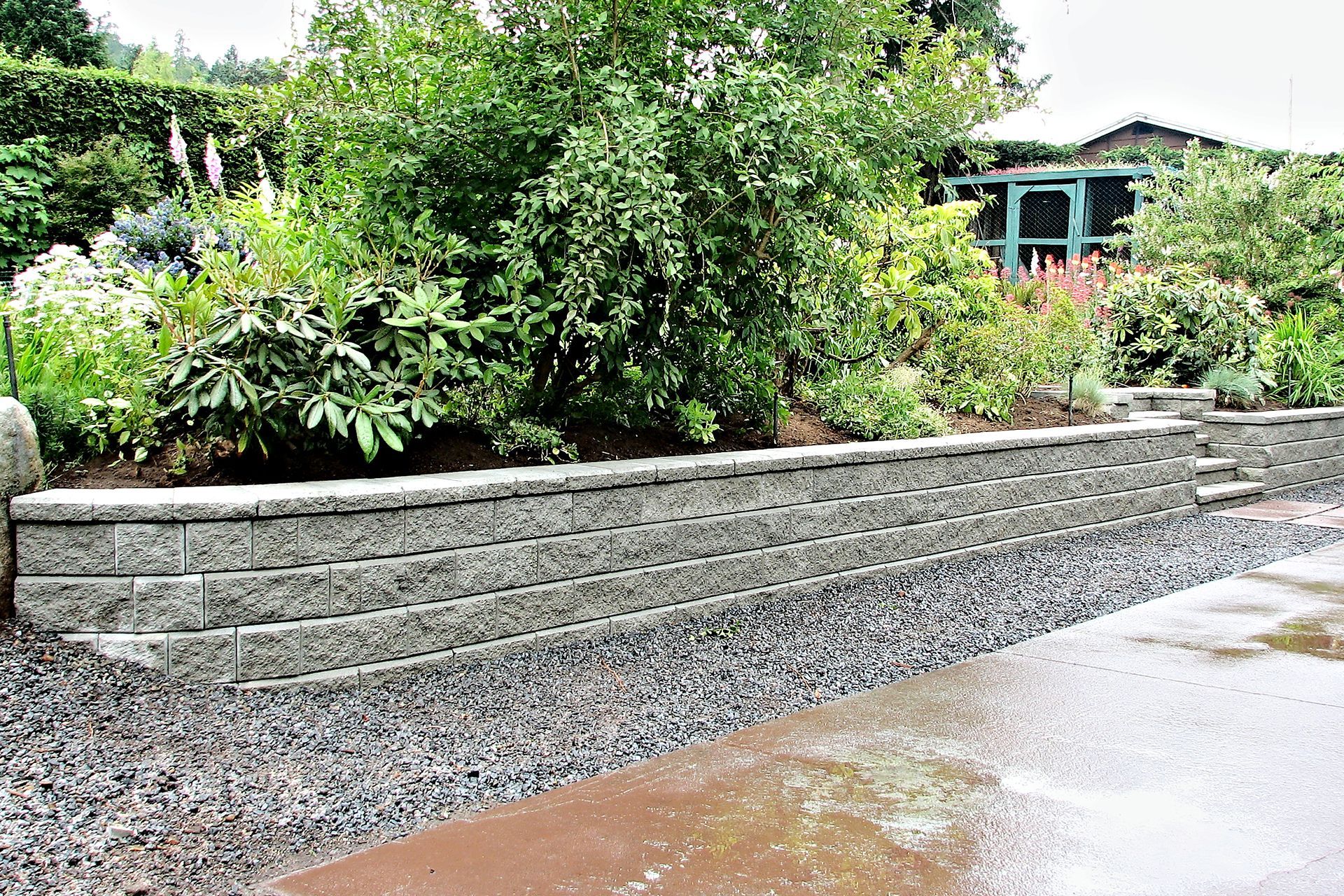 a stone wall surrounds a garden with a gazebo in the background .