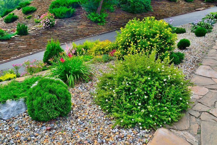 a stone wall surrounds a lush green lawn in front of a house .