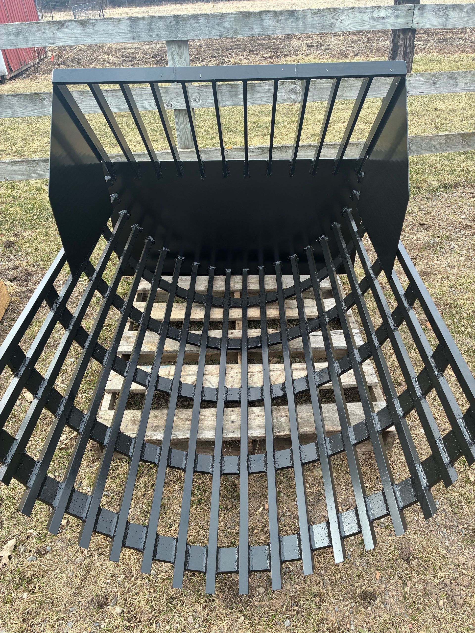 Black skid steer root grapple bucket with curved teeth.