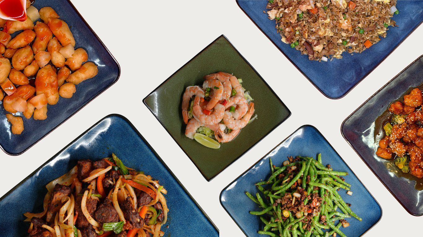 Assorted takeout meals on a table, including fried items, noodles, rice, sushi, and grilled meat.