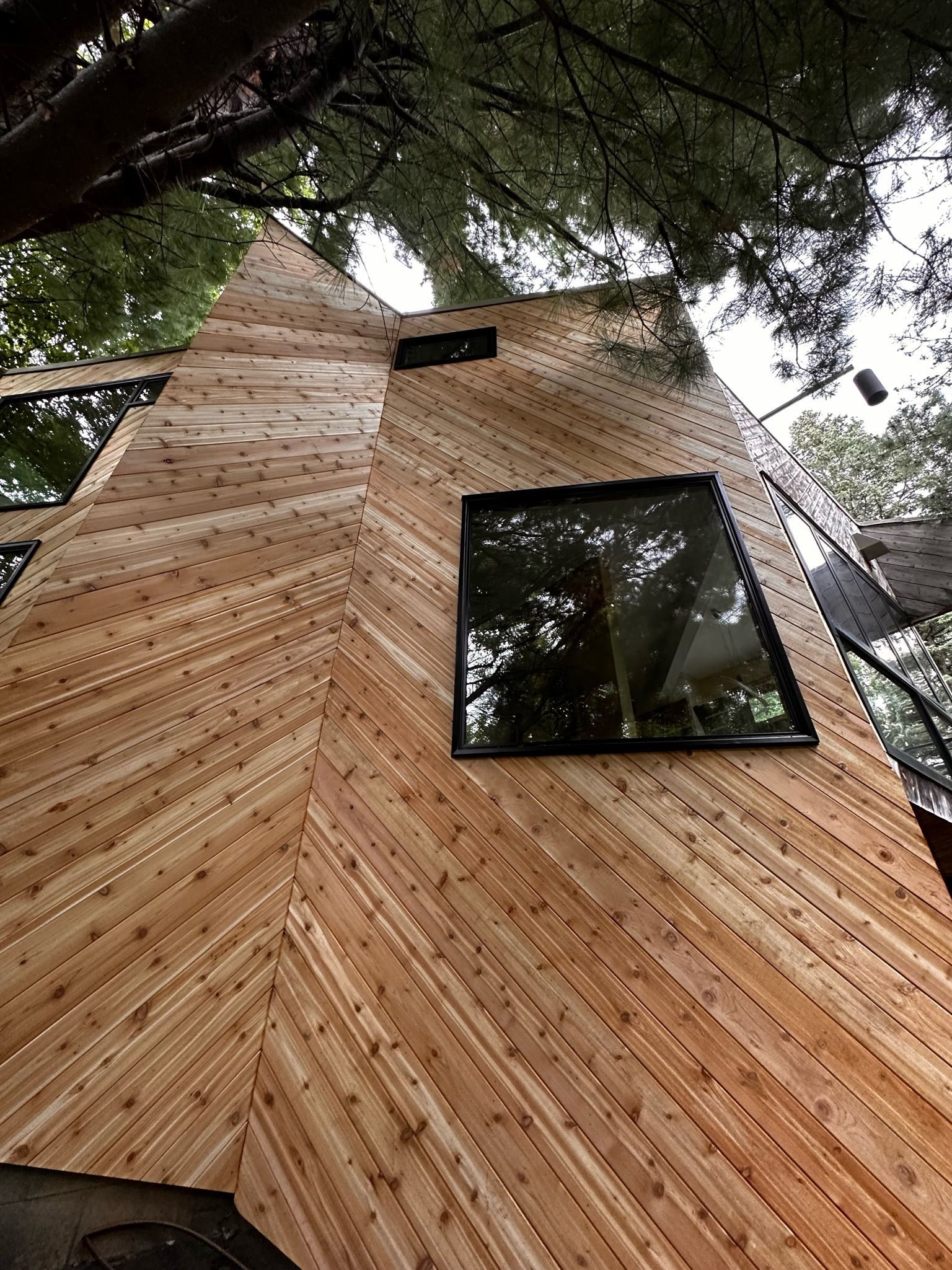 A low-angle view of a modern building exterior featuring light-colored wood siding arranged in a chevron pattern.