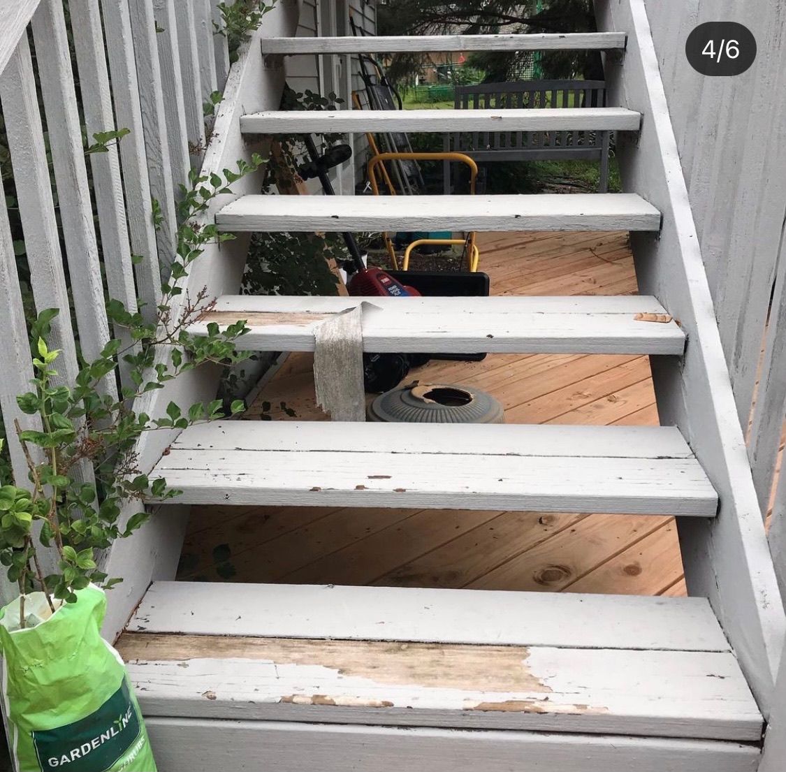 A set of weathered, white-painted wooden outdoor stairs with peeling paint, showing signs of wear.