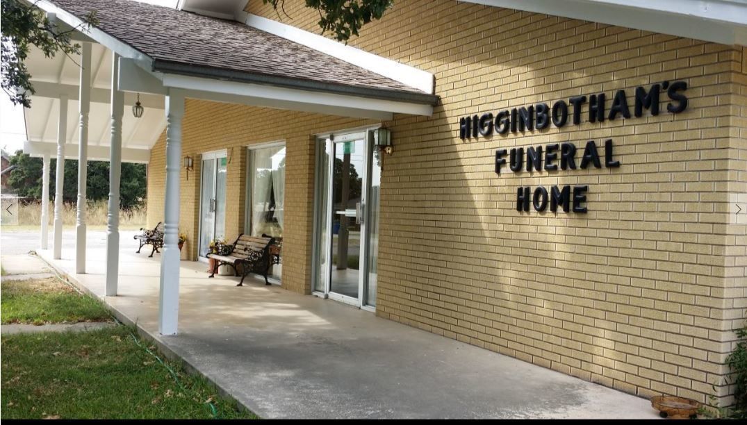 A brick building with a porch and a sign that says hoginbotham 's funeral home.