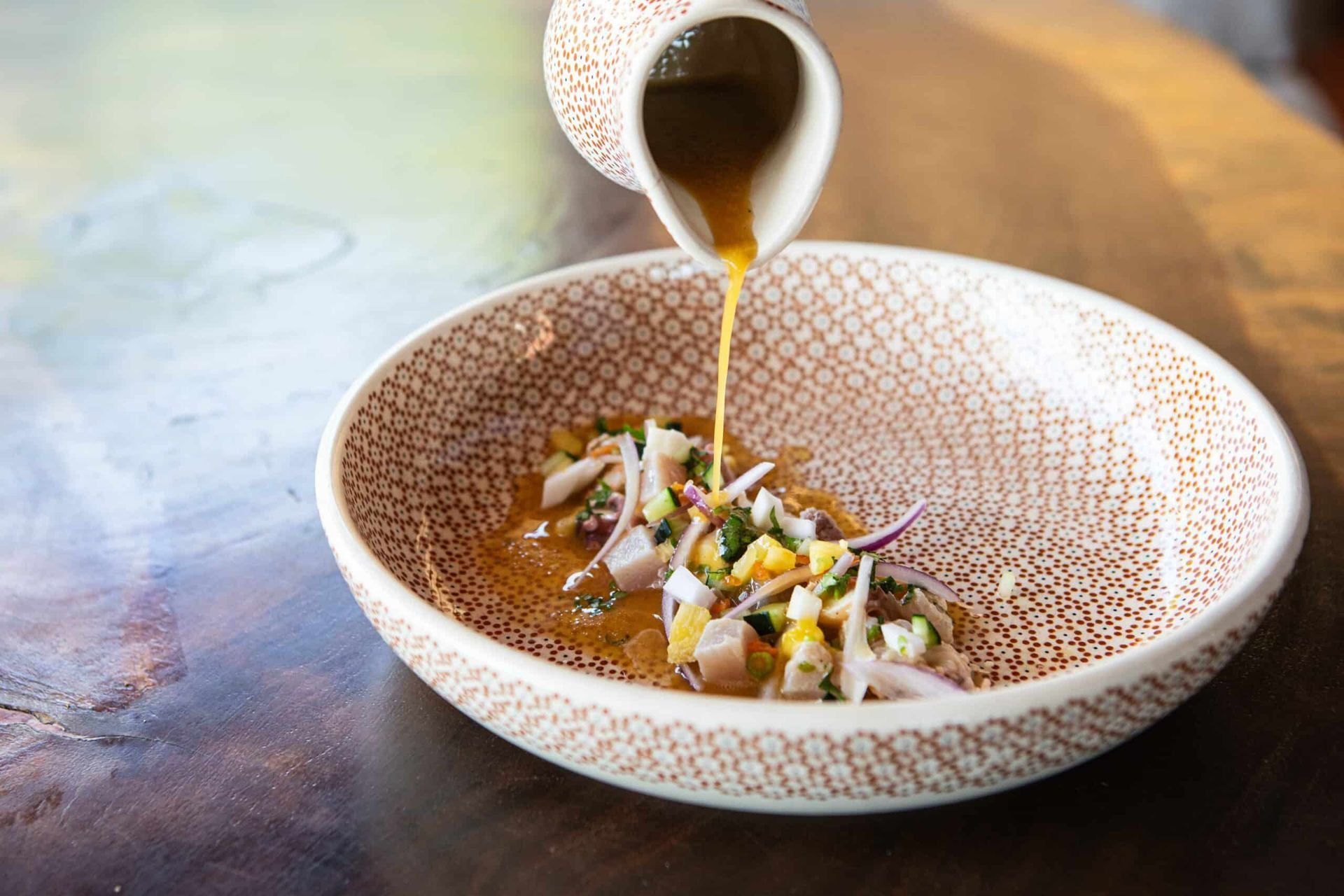 A bowl of food is being poured into a bowl on a table.