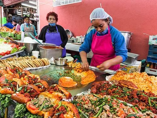Street food vendors serving colorful seafood and vegetable dishes at an outdoor market stall
