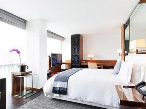 Bright modern bedroom with a large white bed, wood accents, and a window view